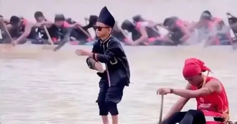 インドネシアのボートレースで船首に立って踊る子ども